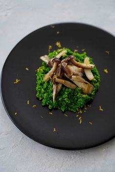 a black plate topped with broccoli and mushrooms