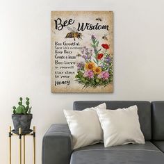 a gray couch sitting next to a white wall with flowers on it and the words bee wilson