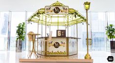 an elaborately decorated carousel in the middle of a room with large windows and potted plants