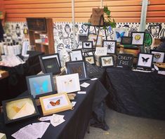 a table covered in pictures and framed art on it's sides with black cloth