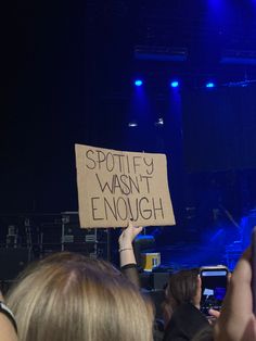 a person holding up a sign that says spotify wasn't enough