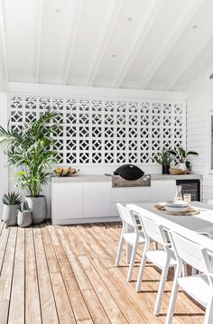 an outdoor dining area with white chairs and wooden flooring is featured in this image