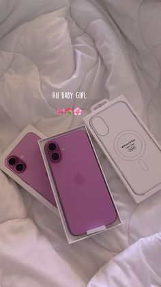 two iphones are sitting on a bed with the packaging in front of them, and one is pink