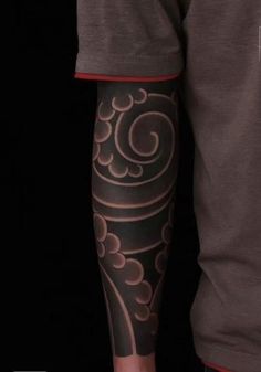 a man with a tattoo on his arm is standing in front of a black background