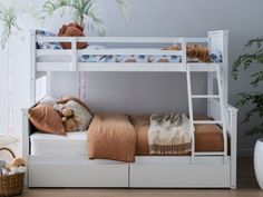 a white bunk bed sitting next to a potted plant and stuffed animals on top of it