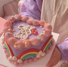 a heart shaped cake with the word love spelled in frosting and rainbows on top