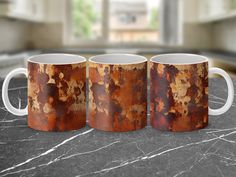 three rusted coffee mugs sitting on top of a marble counter next to a window