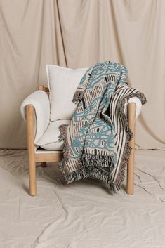 a chair with a blanket on top of it in front of a beige wall and floor