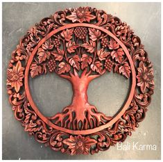 an intricately carved wooden wall hanging depicting a tree with leaves and flowers in the center