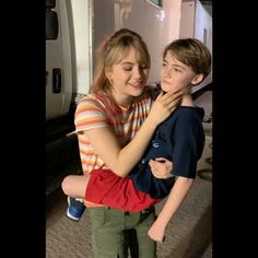 a woman hugging a young boy in front of a refrigerator