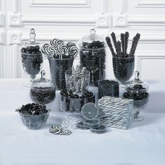 an assortment of candies and chocolates in glass containers on a white tablecloth