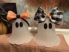 two white ghost statues with black and orange bows on their heads are sitting on a table