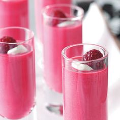 three glasses filled with raspberry smoothie and whipped cream