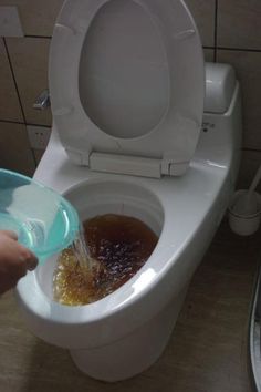 a person is pouring liquid into a toilet with the lid up and it's seat down