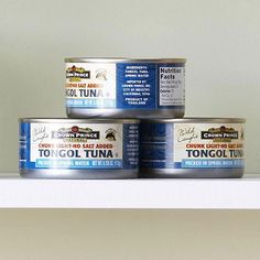 three cans of canned tuna sit on a shelf