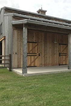 two large wooden garages sitting on top of a lush green field