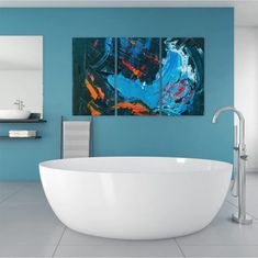 a bath tub sitting under two paintings in a bathroom