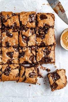 chocolate chip brownies cut into squares on top of parchment paper next to a knife