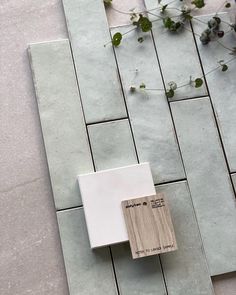 a tile floor with a wooden block on it and flowers growing in the corner next to it