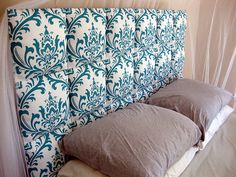 an upholstered headboard with blue and white damask on the wall behind it