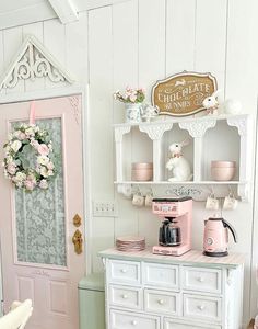 a pink and white dollhouse kitchen with an old fashioned coffee maker on the counter