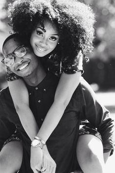 a man holding a woman on his back while she smiles at the camera with her arms around him