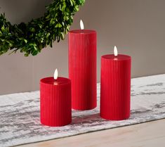 three red candles sitting on top of a table