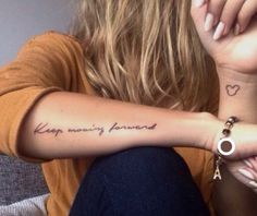 a woman with a tattoo on her arm that says, keep moving forward and heart