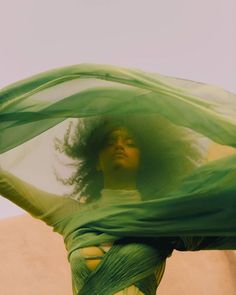 a woman in a green dress with her hair flying through the air and covering her face