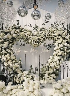 a white wedding arch with flowers and chandeliers