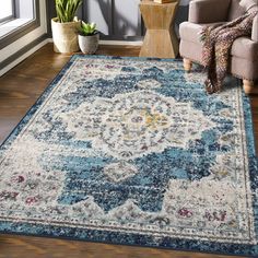 a blue and white area rug with an ornate design on the floor in front of a chair