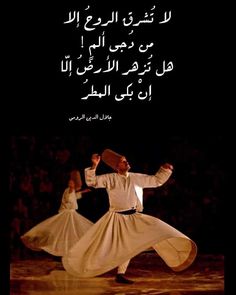 two men in white clothes are dancing with arabic writing on the wall behind them, and one man has his arm raised