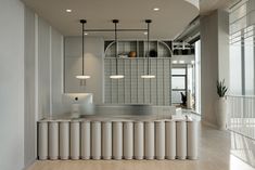 a modern kitchen with an island counter and hanging lights in the ceiling, along with white tiles on the walls