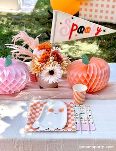 a table topped with paper pumpkins and plates