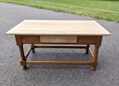 a wooden table sitting on top of a gravel road next to a grass covered field