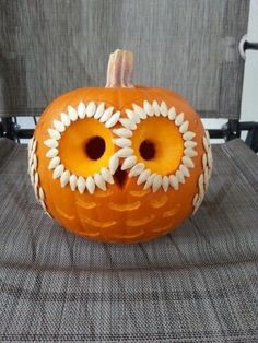 a pumpkin decorated with an owl's eyes and flowers is sitting on a chair