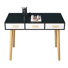 a black and white desk with two drawers on it's legs, next to a magazine