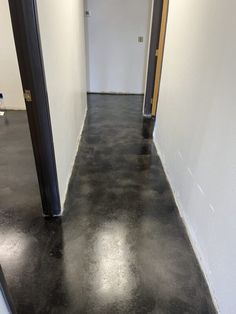 an empty hallway with white walls and black floors