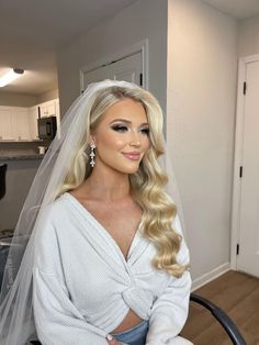 a woman with blonde hair wearing a wedding veil and sitting on a chair in front of a kitchen