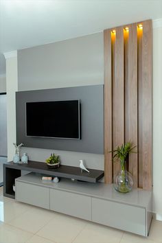 a flat screen tv mounted to the side of a wall next to a vase with plants