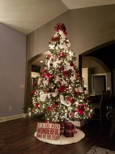 a christmas tree decorated with red and white ornaments is in the middle of a living room