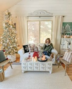 a woman sitting on a couch in front of a christmas tree