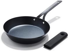 an empty frying pan and spatula on a white surface