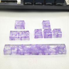 several pieces of purple marble sitting on top of a white table next to a keyboard