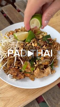 someone is adding lime to a plate of food on a wooden table with the words pad thai above it