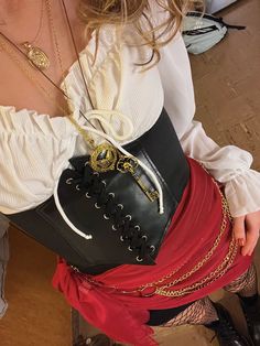 a woman wearing a skirt and boots with chains around her waist, holding a purse