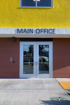 the main office building has two glass doors and is yellow with white lettering on it