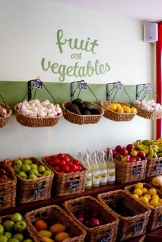 fruit and vegetables are displayed in baskets on the wall