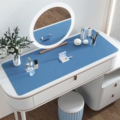 a blue and white vanity table with a round mirror on it's facet