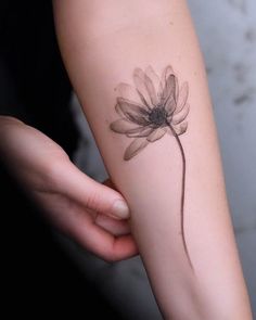 a woman's arm with a flower tattoo on the left side of her arm